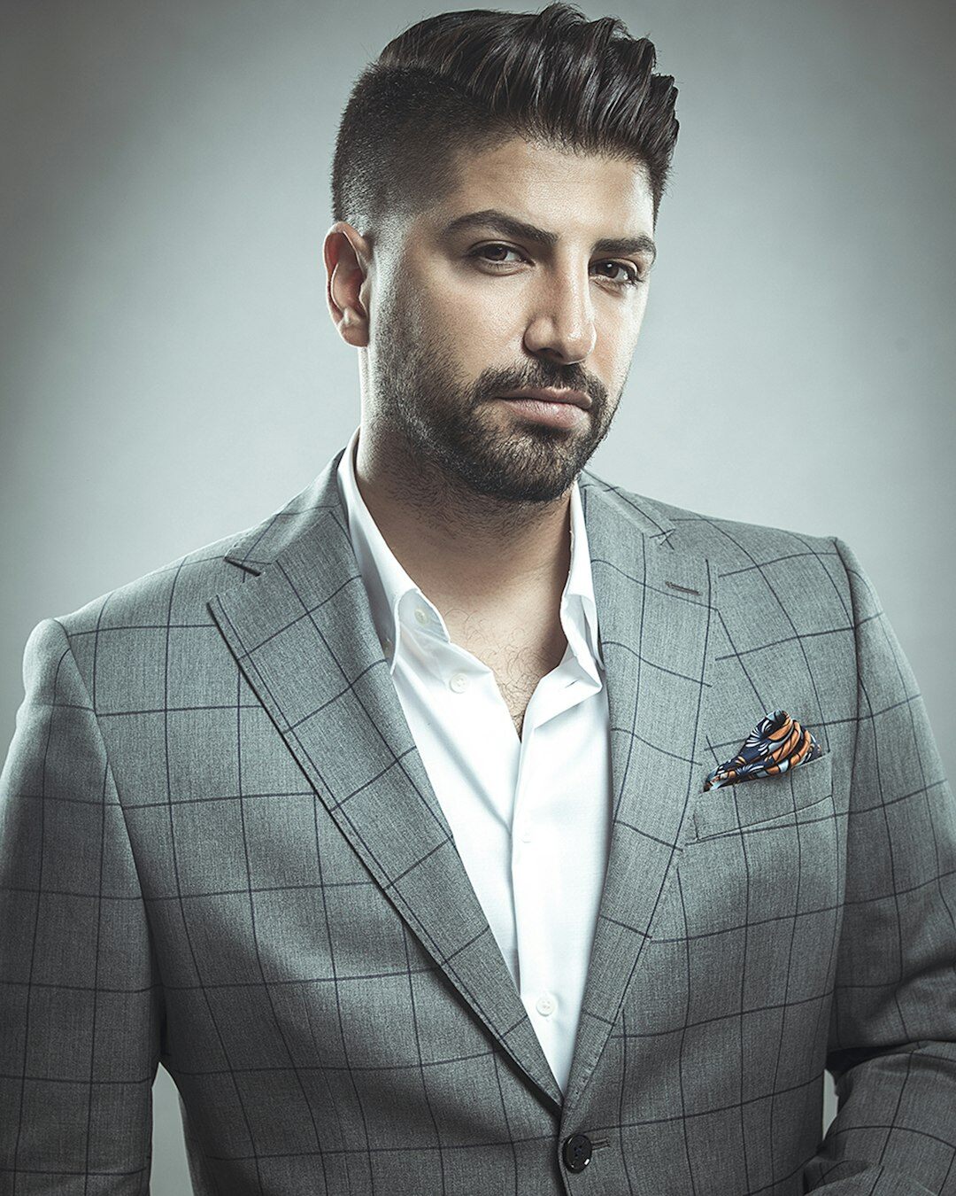 Studio portrait of a Turkish man in his forties wearing a smart blazer