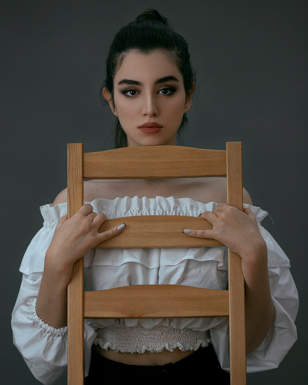 Studio portrait of a young Turkish woman with curly hair wearing a blouse